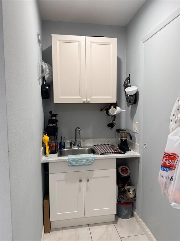 A small kitchen area features white cabinets, a stainless steel sink, and light-colored tile flooring — 8209 VASSAR CIRCLE, TAMPA, FL