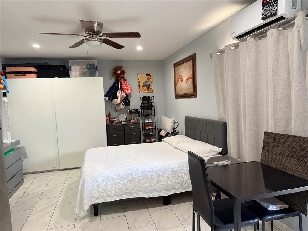 A bedroom features a bed, white wardrobe, small dining table, and tile flooring — 8209 VASSAR CIRCLE, TAMPA, FL