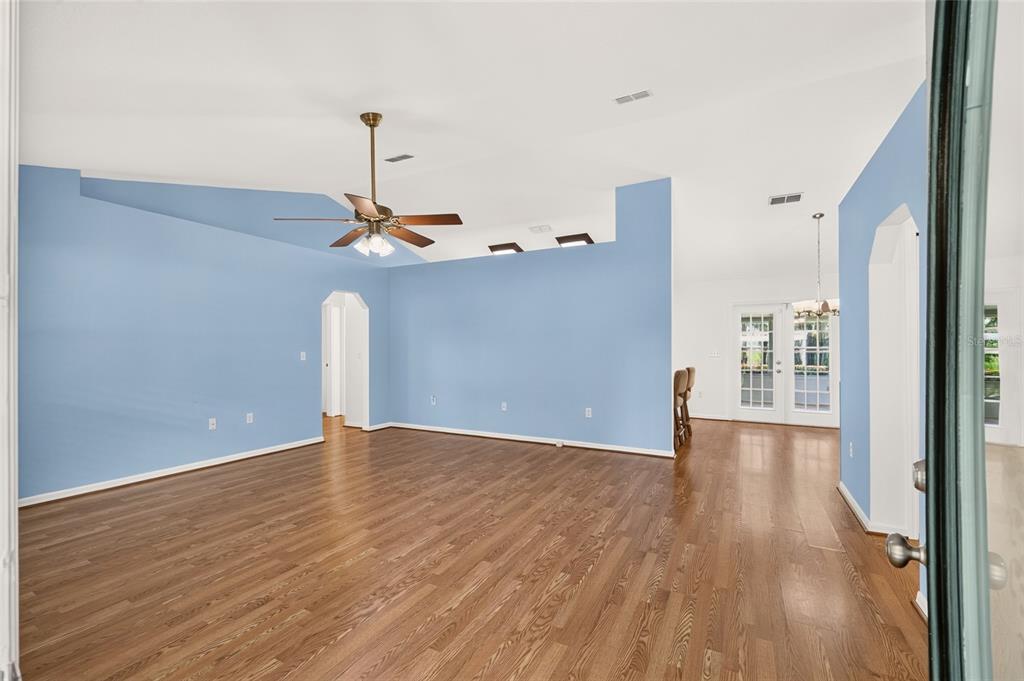A spacious living room with blue walls, hardwood floors, and a vaulted ceiling with fan — 12499 E HIGHWAY 25, OCKLAWAHA, FL