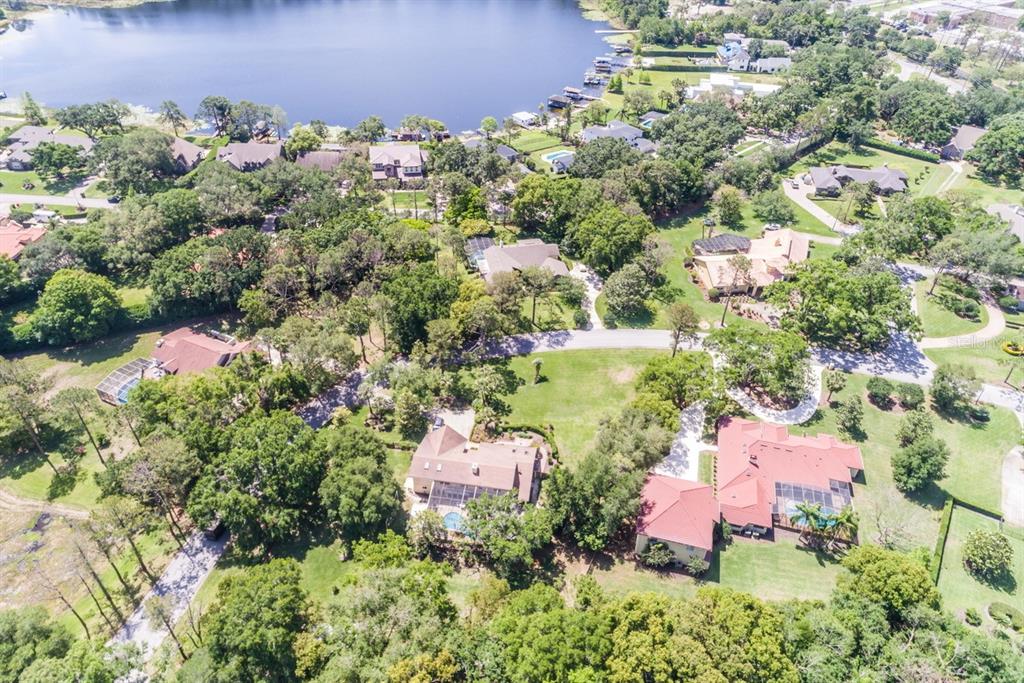 An aerial view shows several houses with swimming pools surrounded by trees and a lake — 11035 SCHOONER WAY, WINDERMERE, FL