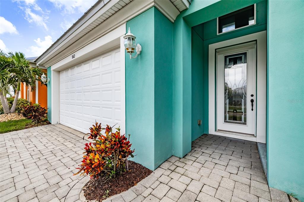 A teal house exterior features a white garage door, a front door with glass, and pavers — 562 BIMINI BAY BOULEVARD, APOLLO BEACH, FL