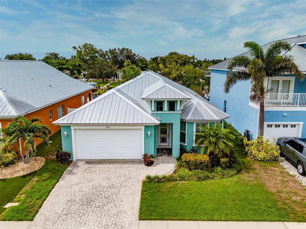 A teal single-story house with a metal roof and a paved driveway sits between neighbors — 562 BIMINI BAY BOULEVARD, APOLLO BEACH, FL