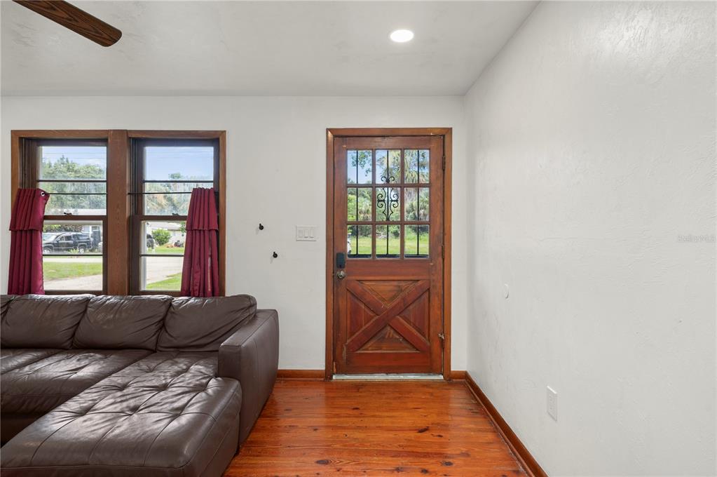 A living room features a brown leather sectional, wood floors, and a wooden front door — 809 BURLAND STREET, PUNTA GORDA, FL