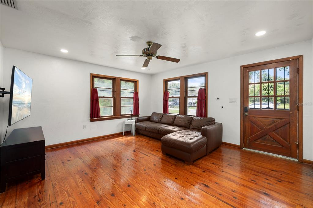 A living room features hardwood floors, a brown sectional sofa, and a wooden front door — 809 BURLAND STREET, PUNTA GORDA, FL