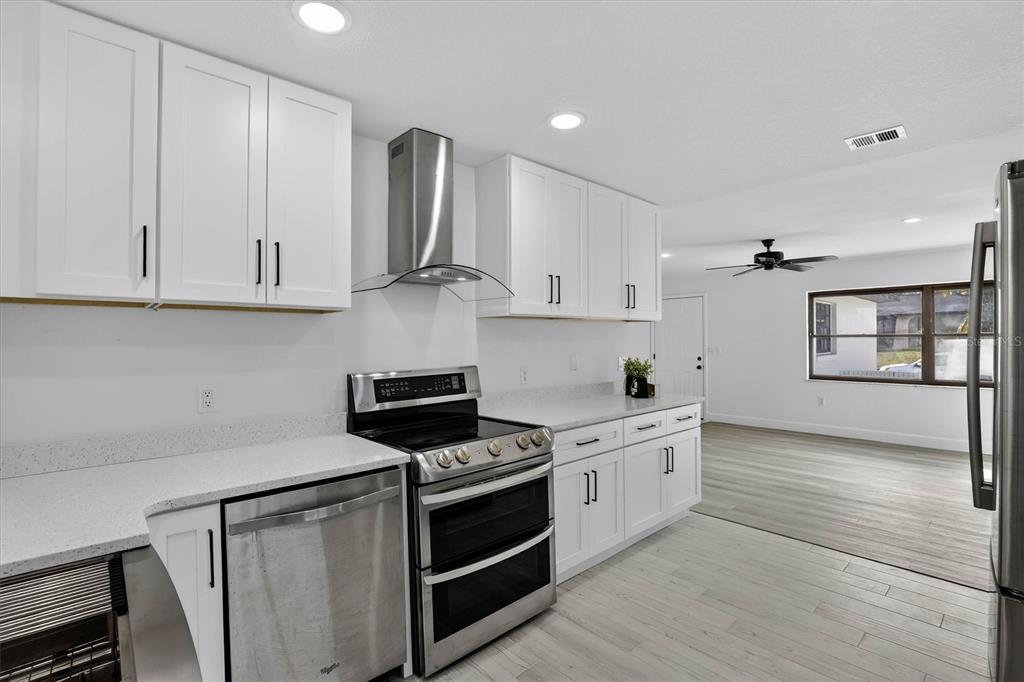 A modern kitchen features white cabinets, stainless steel appliances, and light wood-look flooring — 517 HICKORYWOOD AVENUE, ALTAMONTE SPRINGS, FL