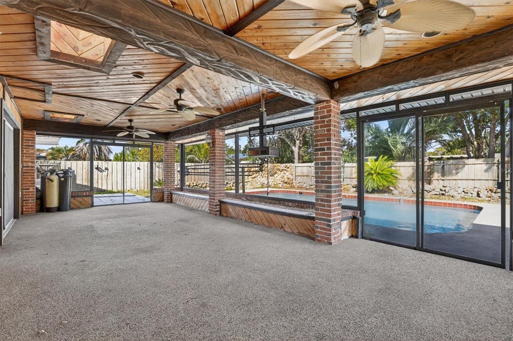 A covered patio features a wood-paneled ceiling, brick pillars, and sliding glass doors overlooking a pool — 517 HICKORYWOOD AVENUE, ALTAMONTE SPRINGS, FL
