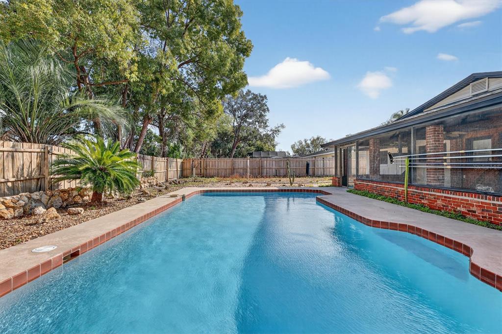 A rectangular swimming pool sits in a backyard with a brick-trimmed patio and wooden fence — 517 HICKORYWOOD AVENUE, ALTAMONTE SPRINGS, FL