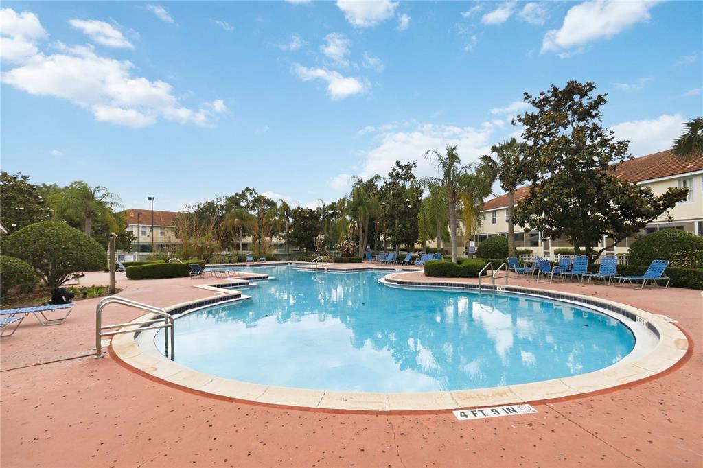A row of three attached townhomes features beige stucco, light blue siding, and concrete driveways — 4729 CORAL CASTLE DRIVE, KISSIMMEE, FL
