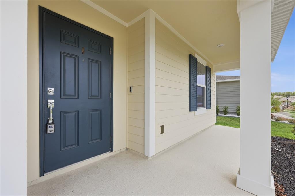 A two-story, light yellow suburban house with a two-car garage and blue shutters — 5215 TANZANITE DRIVE, MOUNT DORA, FL