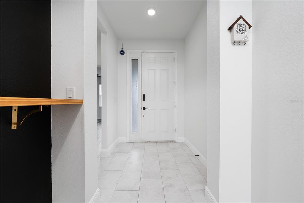 A bright entryway features white walls, light tile flooring, and a white front door — 2591 SEAGIRT WAY, CLERMONT, FL