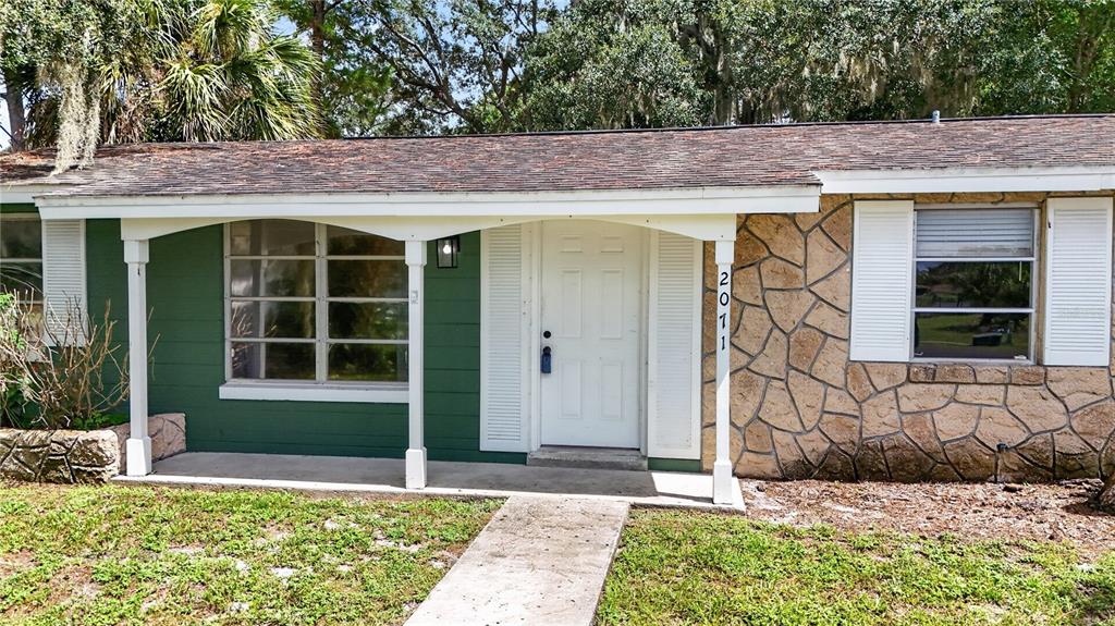 A backyard area features a green house wall, a central tree, and a small gazebo — 2071 CANAL ROAD, DELTONA, FL
