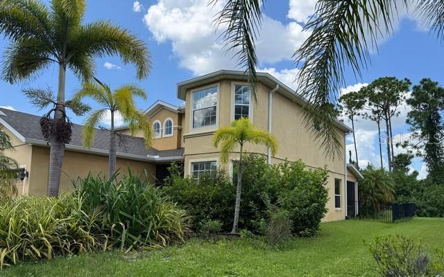 A two-story tan house with a shingled roof and palm trees in the front yard — 2531 HOBBLEBRUSH DRIVE, NORTH PORT, FL