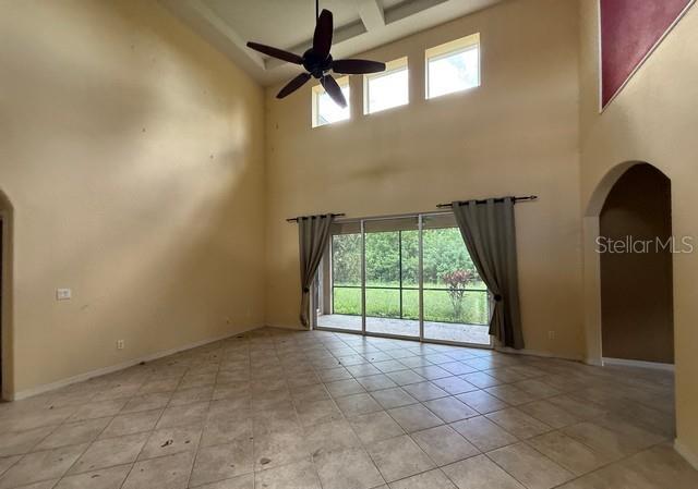 A high-ceilinged living room features tile flooring, a ceiling fan, and sliding glass doors — 2531 HOBBLEBRUSH DRIVE, NORTH PORT, FL