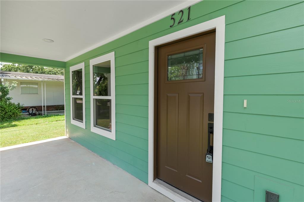 A green house exterior features a brown front door and a concrete porch — 521 SKYLINE DRIVE E, LAKELAND, FL