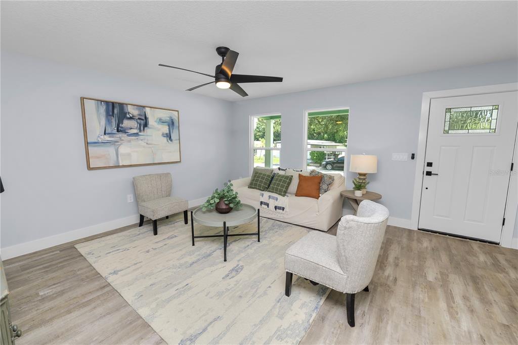 A living room with light gray walls, wood-look flooring, a ceiling fan, and white furniture — 521 SKYLINE DRIVE E, LAKELAND, FL
