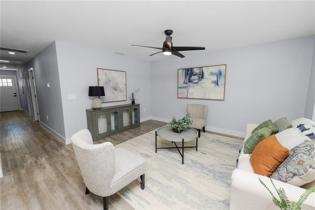 A living room features light gray walls, wood-look flooring, a ceiling fan, and modern furniture — 521 SKYLINE DRIVE E, LAKELAND, FL