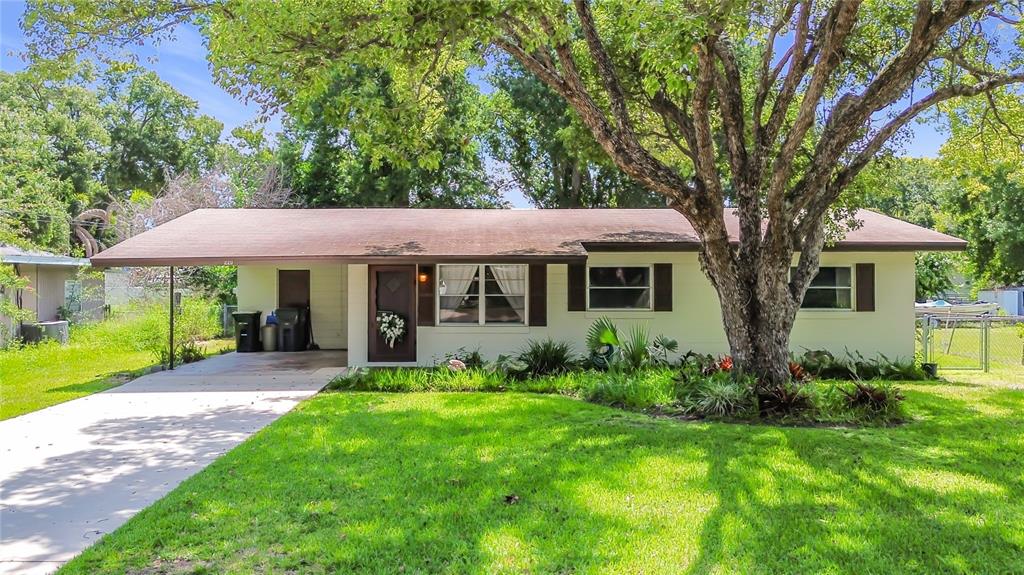 A single-story house with a carport, a large tree in the front yard, and lawn — 220 PINEHURST DR, AUBURNDALE, FL