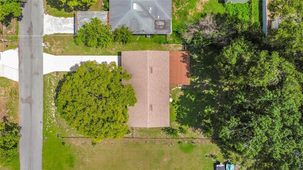 An aerial view shows a house with a brown roof, a driveway, and surrounding trees — 220 PINEHURST DR, AUBURNDALE, FL