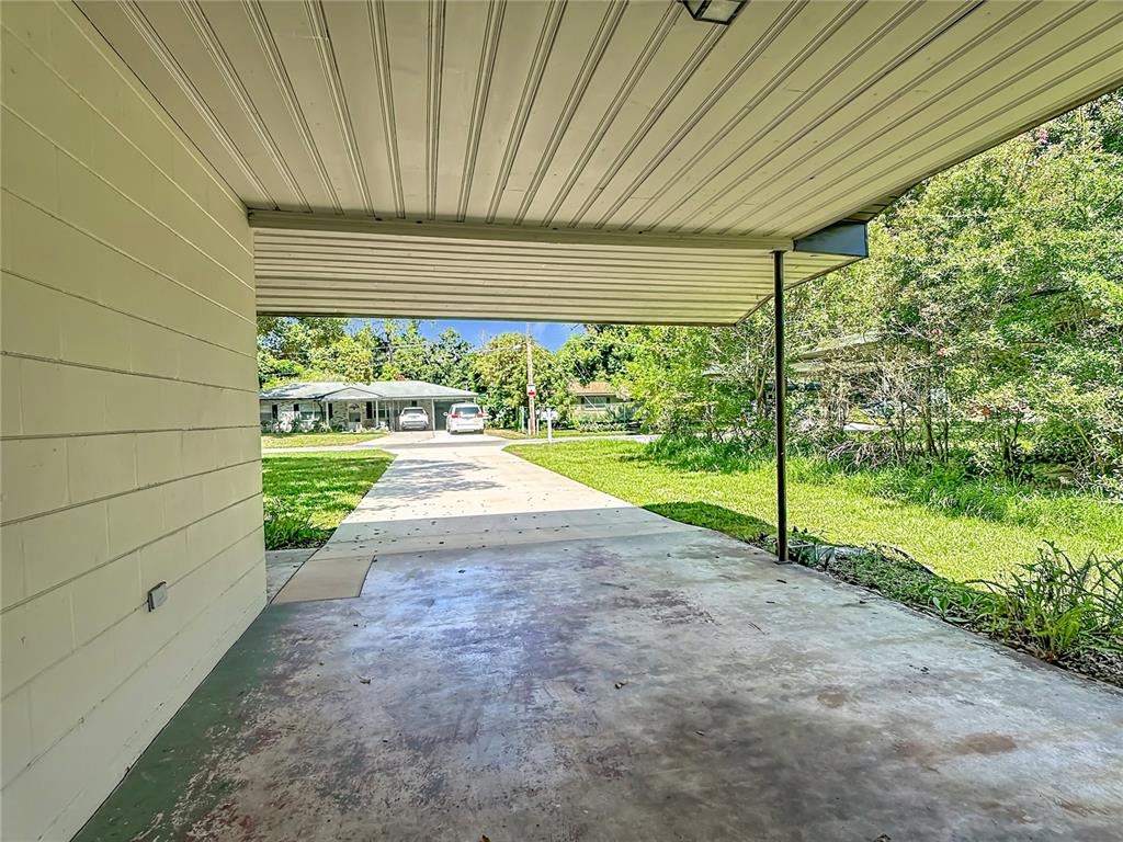 A concrete carport with a metal roof overlooks a driveway and a neighboring house — 220 PINEHURST DR, AUBURNDALE, FL