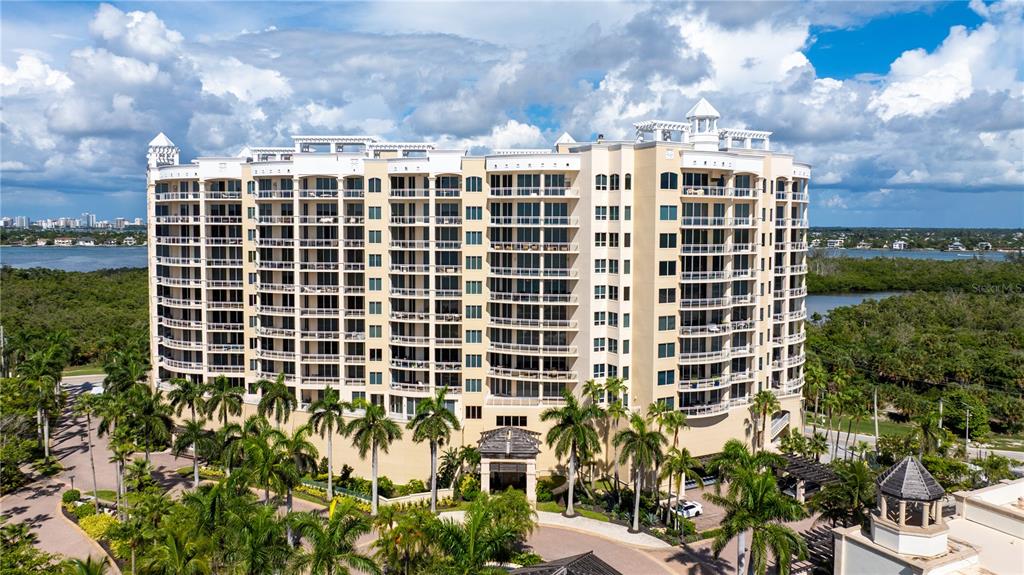 An aerial view of a multi-story residential building surrounded by palm trees and water — 1300 BENJAMIN FRANKLIN DRIVE UNIT 908, SARASOTA, FL
