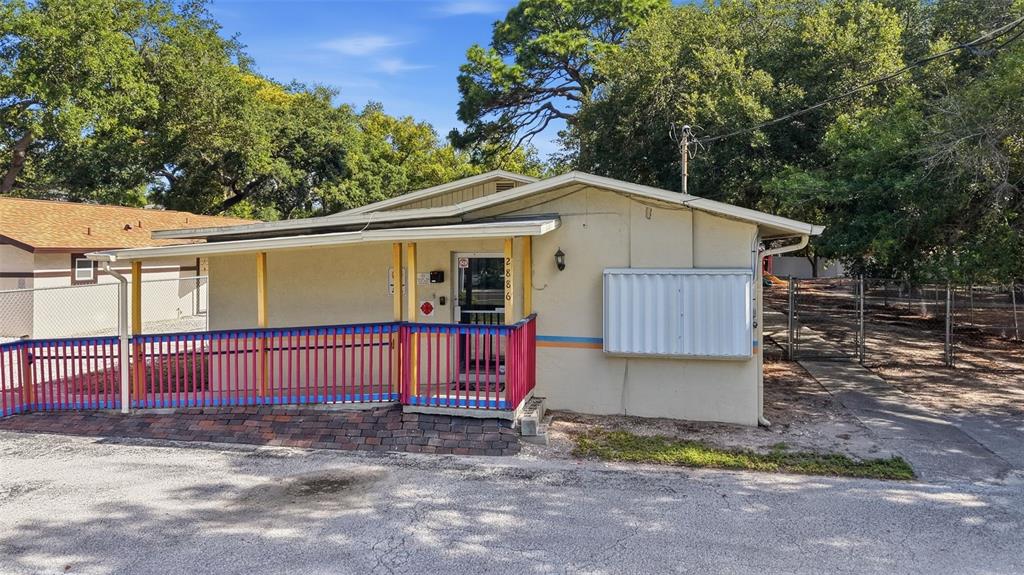 A paved driveway leads to a small yellow building surrounded by trees and grass — 2886 WHITNEY ROAD, CLEARWATER, FL