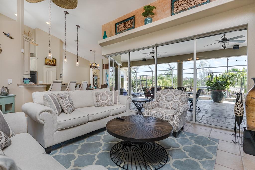 A living room with a sofa, patterned armchair, round coffee table, and sliding glass patio doors — 2317 SW 43RD LANE, CAPE CORAL, FL