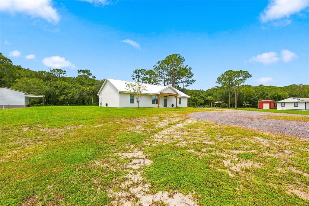 A white single-story house sits on a grassy lot with a gravel driveway — 1315 NE 342ND TRAIL, OKEECHOBEE, FL