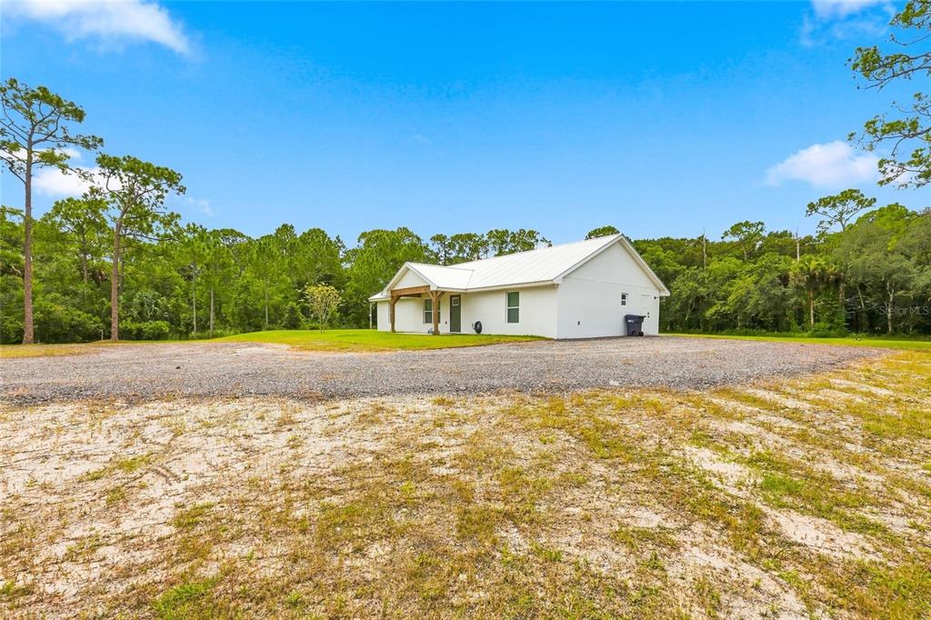 A white single-story house with a metal roof sits on a large gravel lot — 1315 NE 342ND TRAIL, OKEECHOBEE, FL