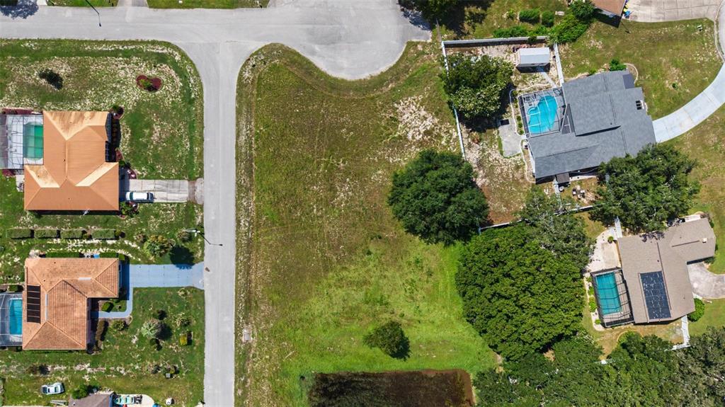 An aerial view shows a vacant residential lot situated between several houses with swimming pools — NORTHWIND COURT, SPRING HILL, FL