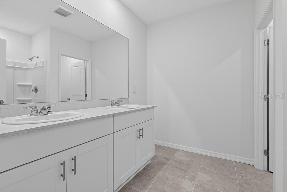 A modern kitchen features white cabinets, stainless steel appliances, and a large quartz island — 6754 EQUINOX LANE, NORTH FORT MYERS, FL