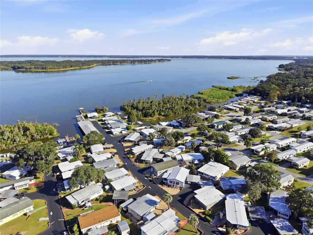 A single-story manufactured home features a screened porch, brick retaining wall, and attached carport — 3896 PICCIOLA ROAD UNIT 411, FRUITLAND PARK, FL