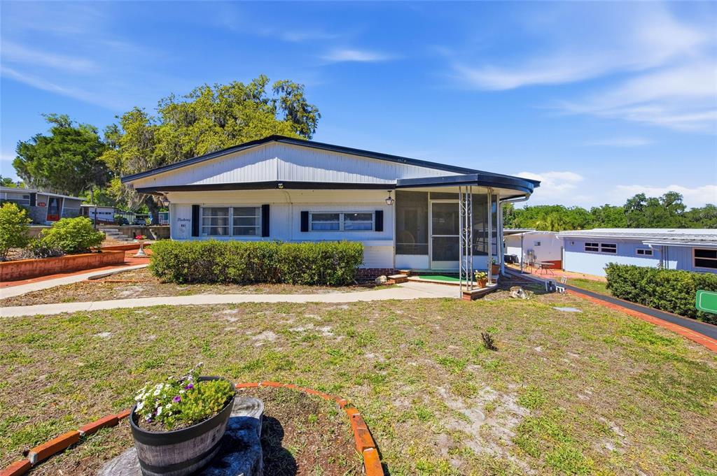 A brick patio with a raised planter bed sits in front of a mobile home — 3896 PICCIOLA ROAD UNIT 411, FRUITLAND PARK, FL