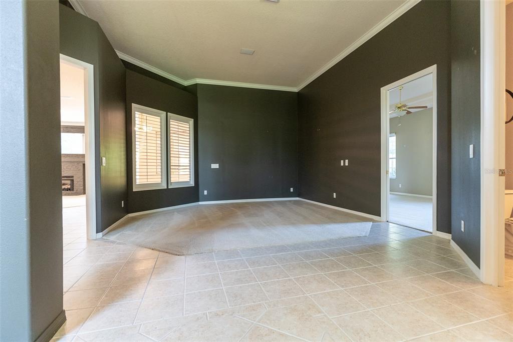 A room with dark walls, beige carpeting, and light-colored tile flooring leads to adjacent rooms — 4818 SE 11TH PLACE, OCALA, FL