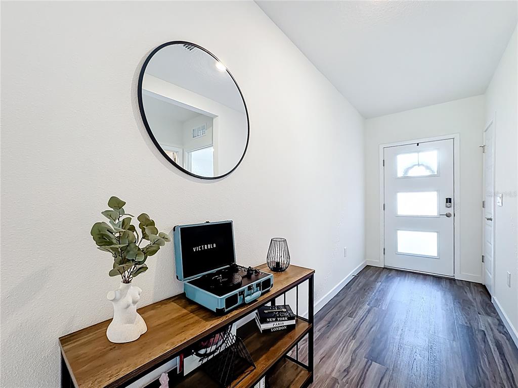 An entryway features a wood console table with a record player, mirror, and front door — 348 TALISI LOOP, ST CLOUD, FL
