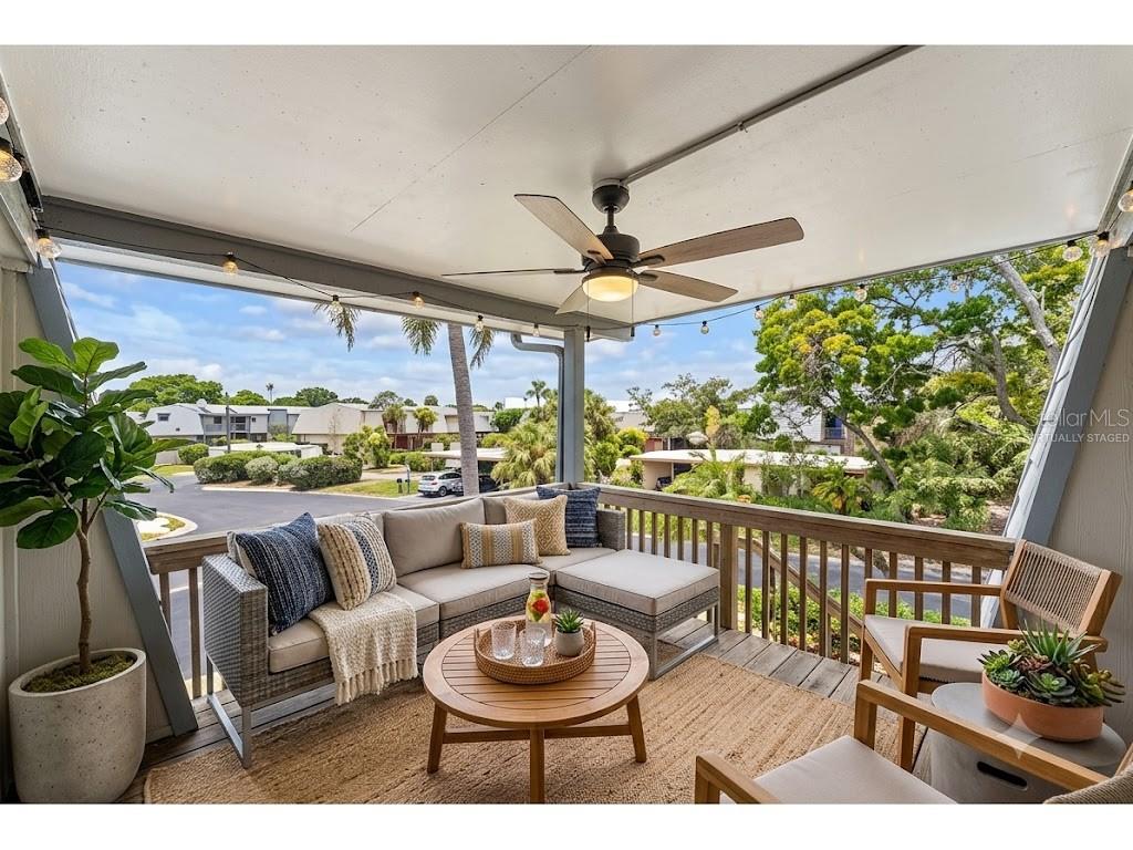 A covered balcony features dark wood flooring, two wicker chairs, potted plants, and a ceiling fan — 14521 CATALINA CIRCLE, SEMINOLE, FL