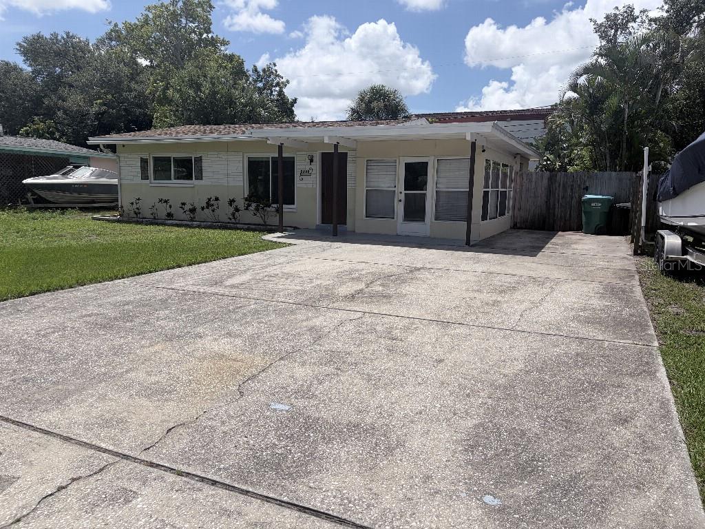 A single-story house with a concrete driveway, a covered porch, and boats parked on both sides — 2209 EUCLID CIRCLE S, CLEARWATER, FL