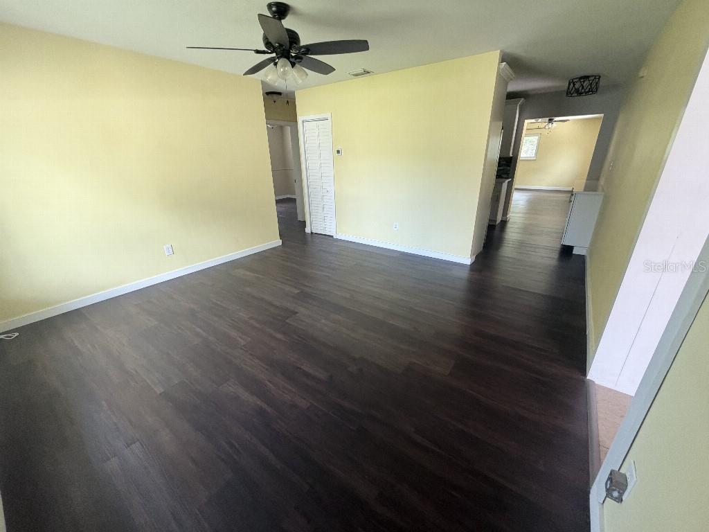 An empty room features yellow walls, dark wood-look flooring, and a ceiling fan — 2209 EUCLID CIRCLE S, CLEARWATER, FL