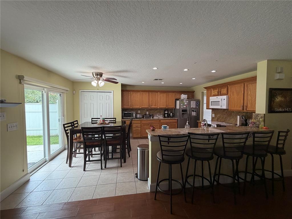 A kitchen with wood cabinets, granite countertops, and a breakfast bar with four stools — 312 WINDROSE DRIVE, ORLANDO, FL