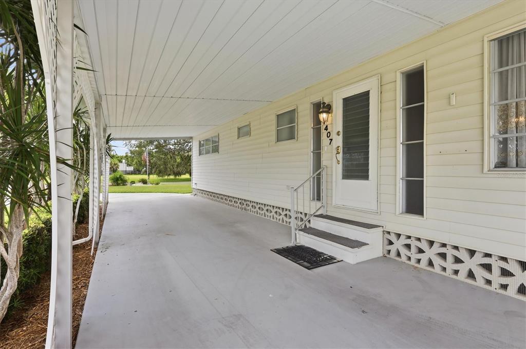 A concrete carport leads to the front entrance of a light-colored mobile home — 1407 41ST AVENUE E, ELLENTON, FL