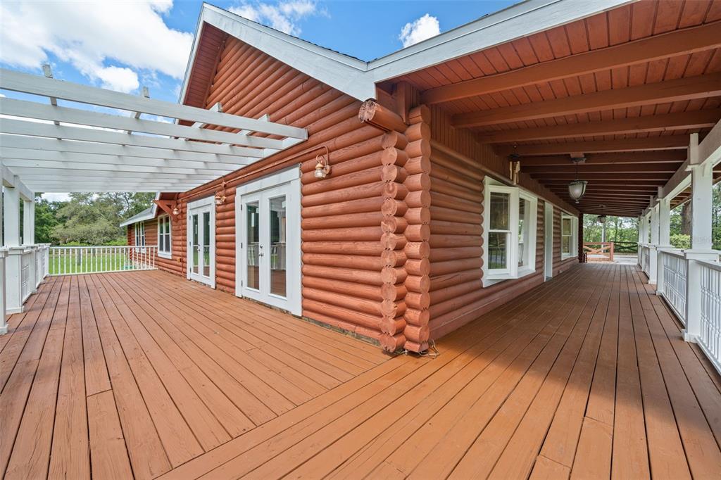 A wide wooden deck wraps around the exterior of a log cabin home — 18441 OAKLAWN DRIVE, SPRING HILL, FL