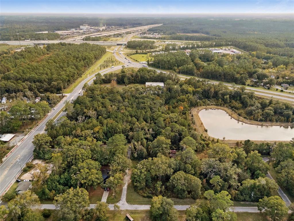 An aerial view shows a wooded lot with a small pond and nearby highway infrastructure — 660 US HIGHWAY 301 S, BALDWIN, FL