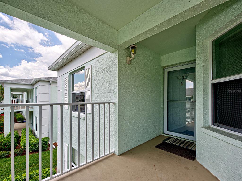 A covered balcony with a white railing overlooks a grassy area and adjacent building — 5725 GREENWOOD AVENUE UNIT 9201, NORTH PORT, FL