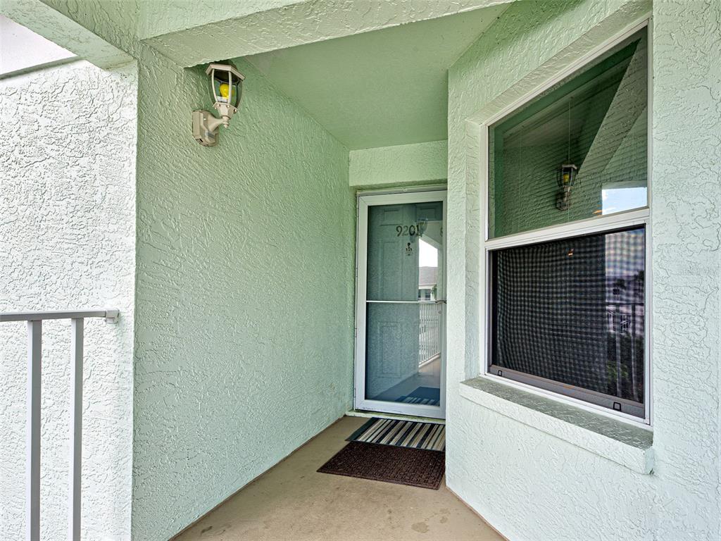 A light green stucco entryway features a screen door, a window, and a wall lamp — 5725 GREENWOOD AVENUE UNIT 9201, NORTH PORT, FL