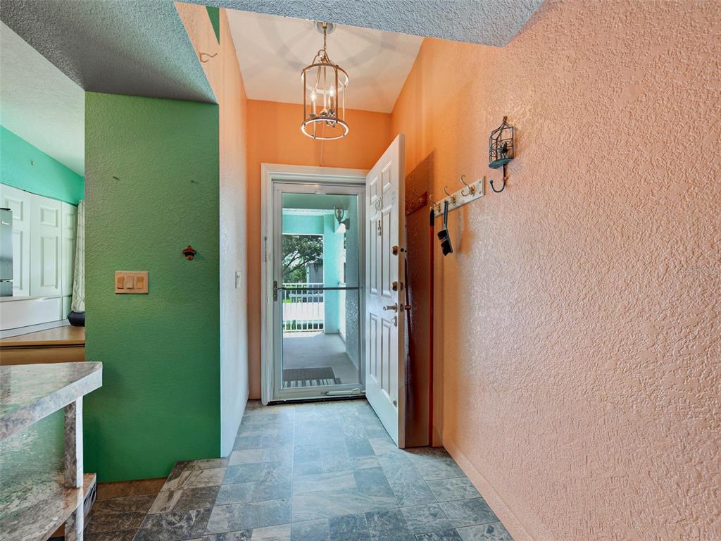 An entryway features a green wall, a peach-colored wall, tile flooring, and an open door — 5725 GREENWOOD AVENUE UNIT 9201, NORTH PORT, FL