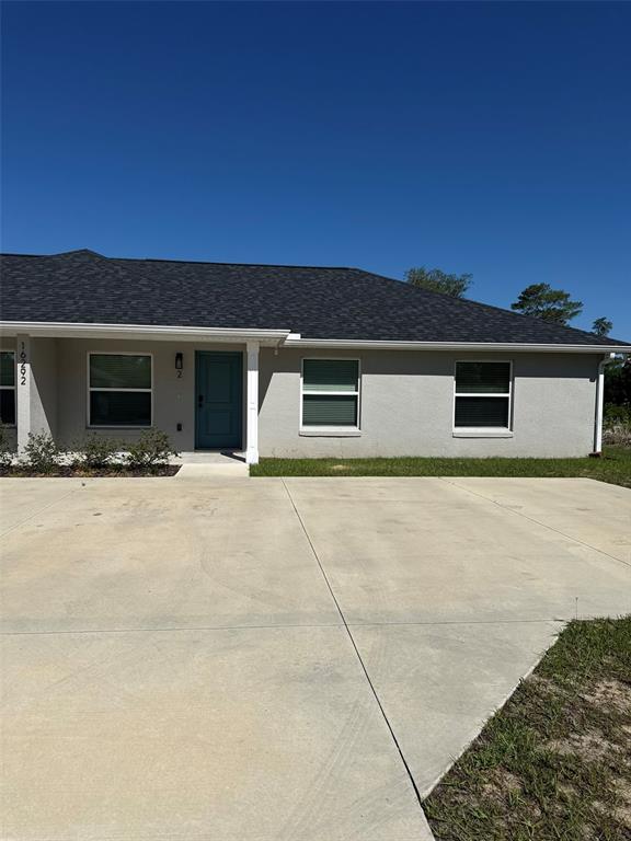 A single-story house with a gray stucco exterior, dark shingled roof, and a concrete driveway — 16292 SW 30 TERRACE UNIT 1, OCALA, FL