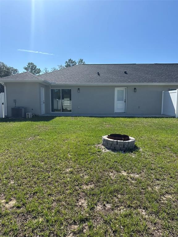 The exterior of a house features a gray stucco wall, a sliding door, and a fire pit — 16292 SW 30 TERRACE UNIT 1, OCALA, FL