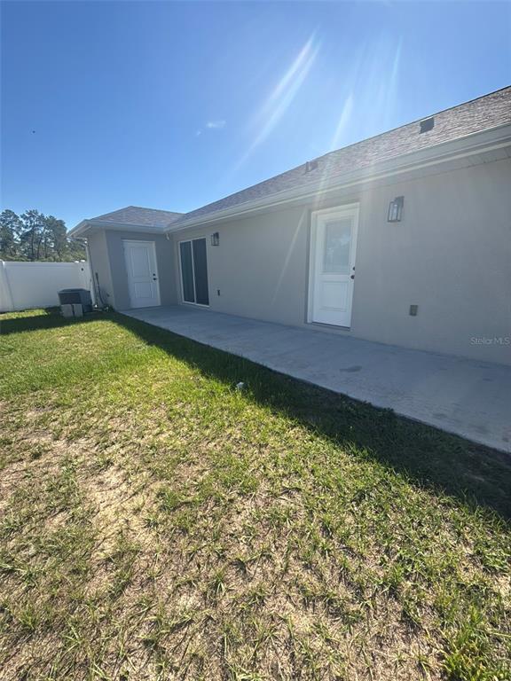 The exterior of a house features a concrete patio, a sliding glass door, and two doors — 16292 SW 30 TERRACE UNIT 1, OCALA, FL