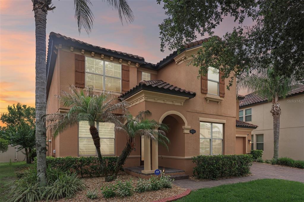 A two-story stucco house with a tiled roof, arched entryway, and a paved driveway — 9117 OUTLOOK ROCK TRAIL, WINDERMERE, FL