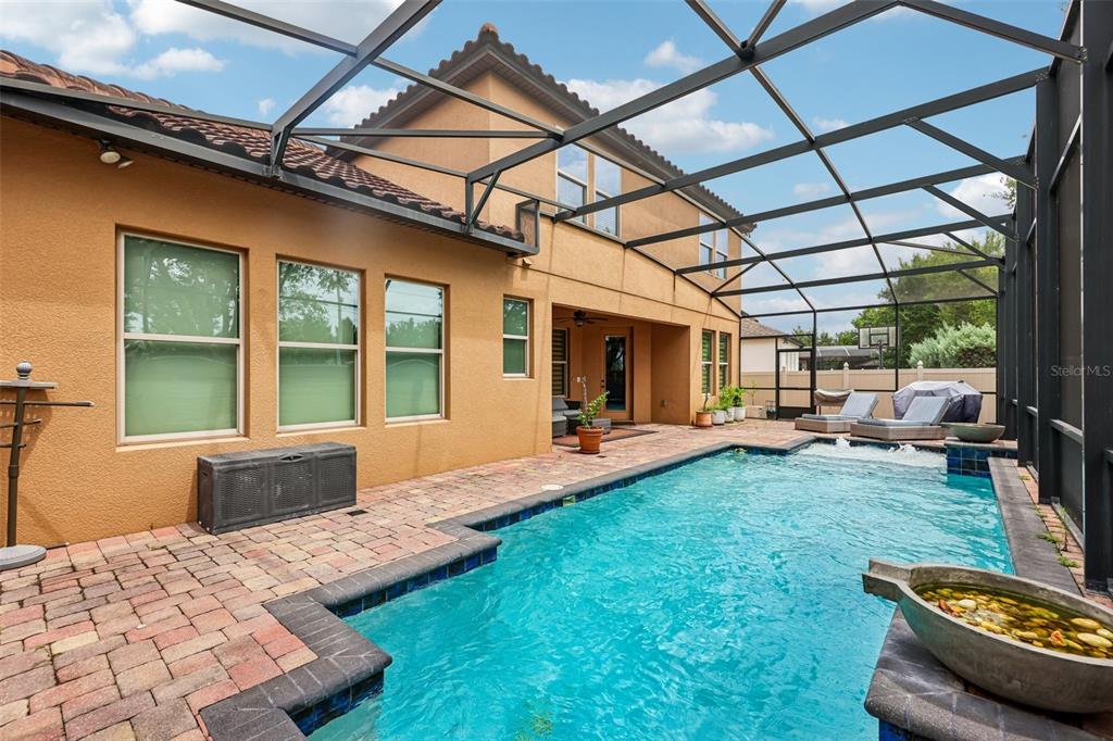 A screened-in patio features a swimming pool, brick pavers, and a two-story tan house — 9117 OUTLOOK ROCK TRAIL, WINDERMERE, FL