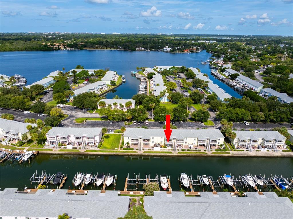 An aerial view shows a waterfront condominium complex with boat slips and a parking lot — 5132 BEACH DRIVE SE UNIT C, ST PETERSBURG, FL